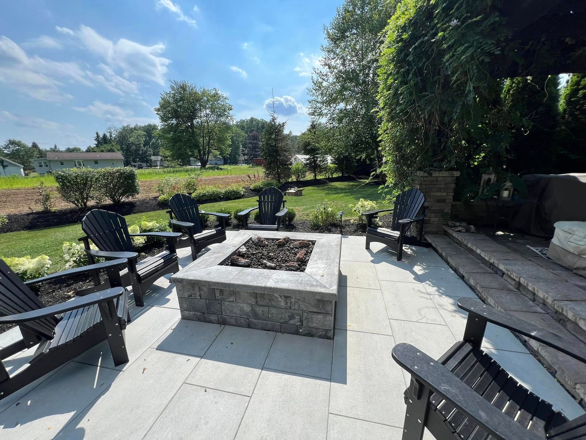 There is a fire pit on the patio with chairs around it.