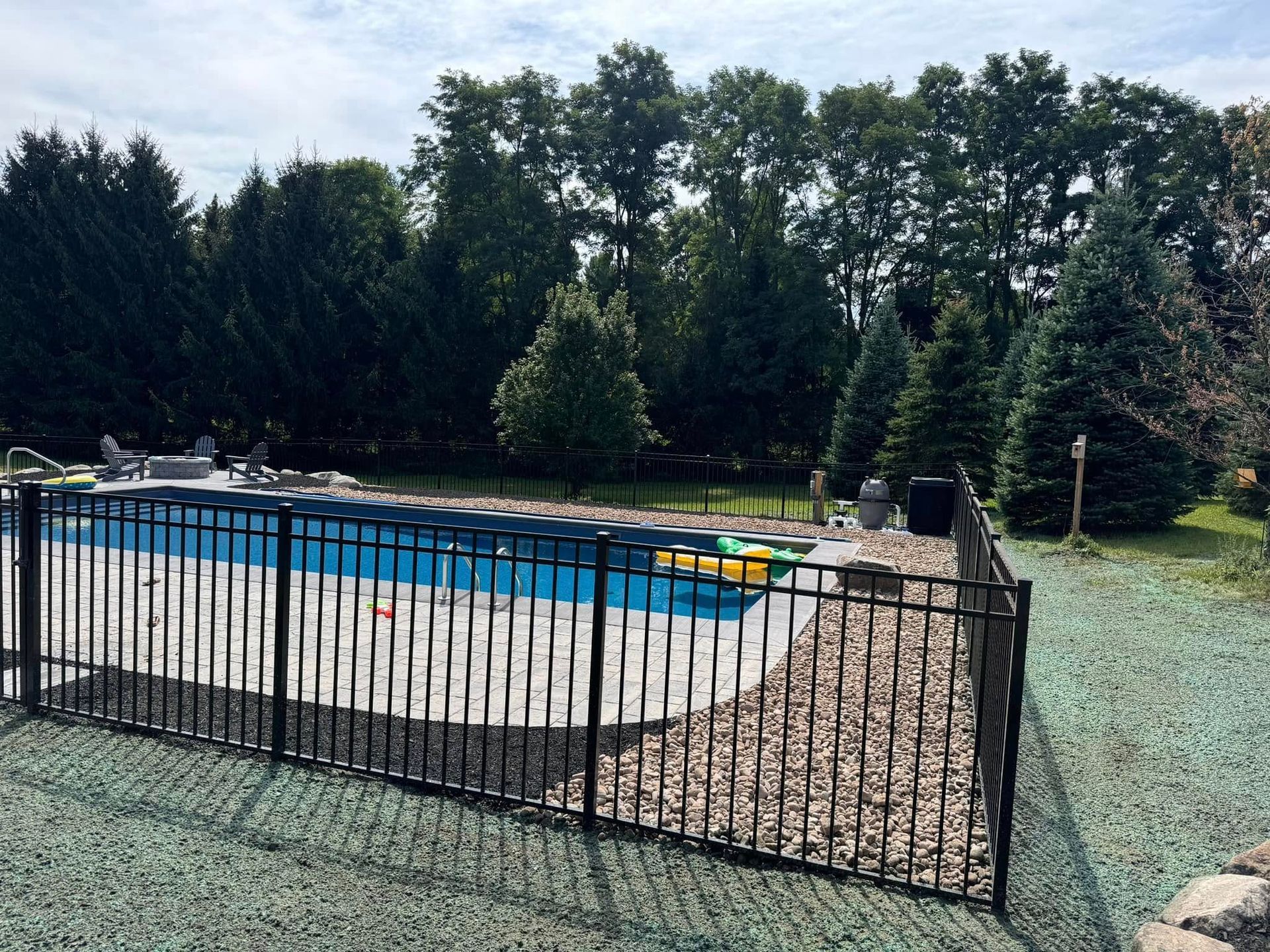 A fence surrounds a large swimming pool in a backyard