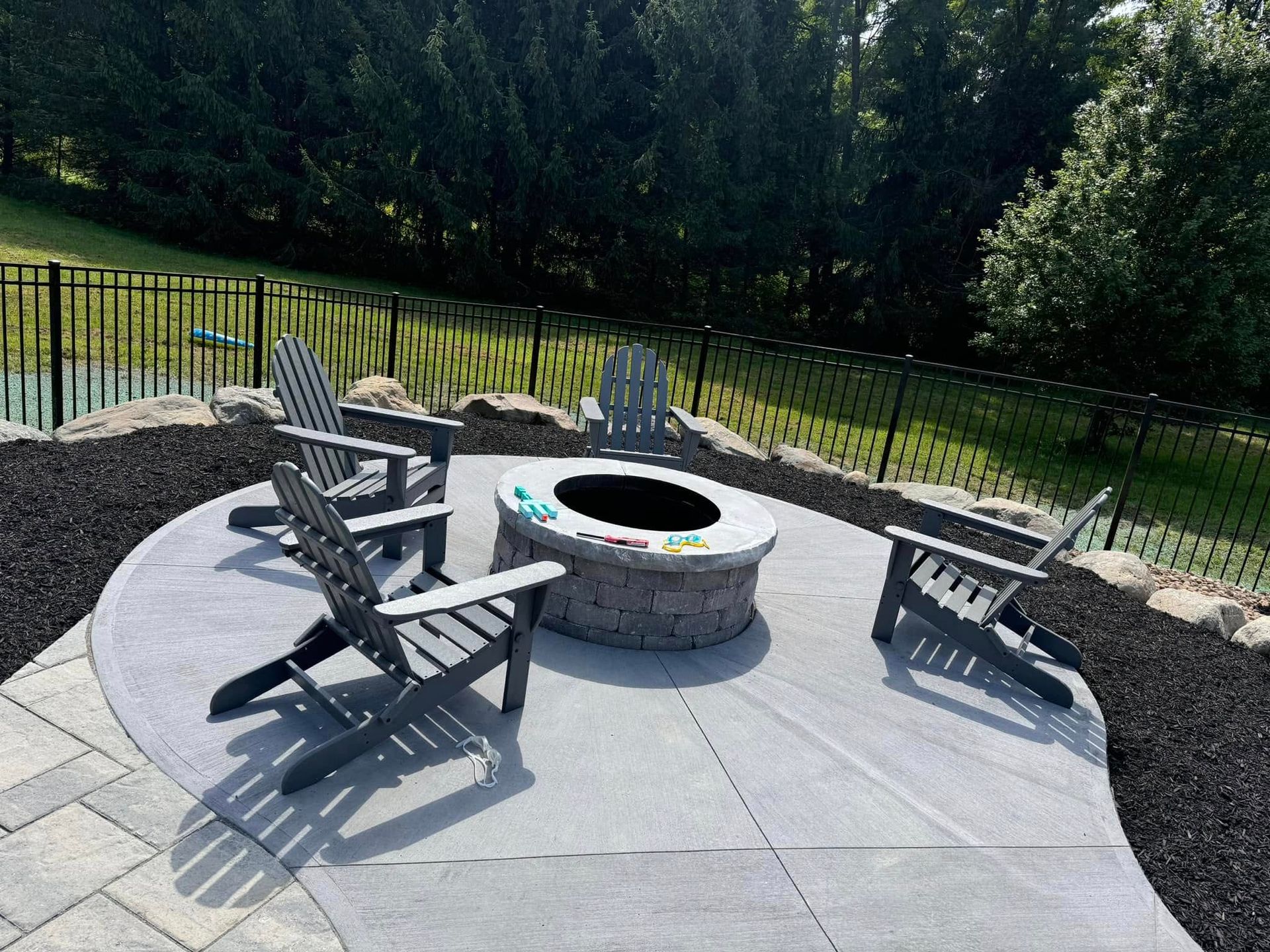 A fire pit is surrounded by chairs on a patio.