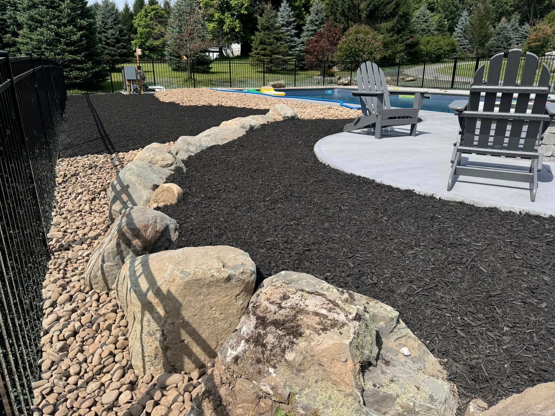 A fence surrounds a patio area with chairs and a pool.