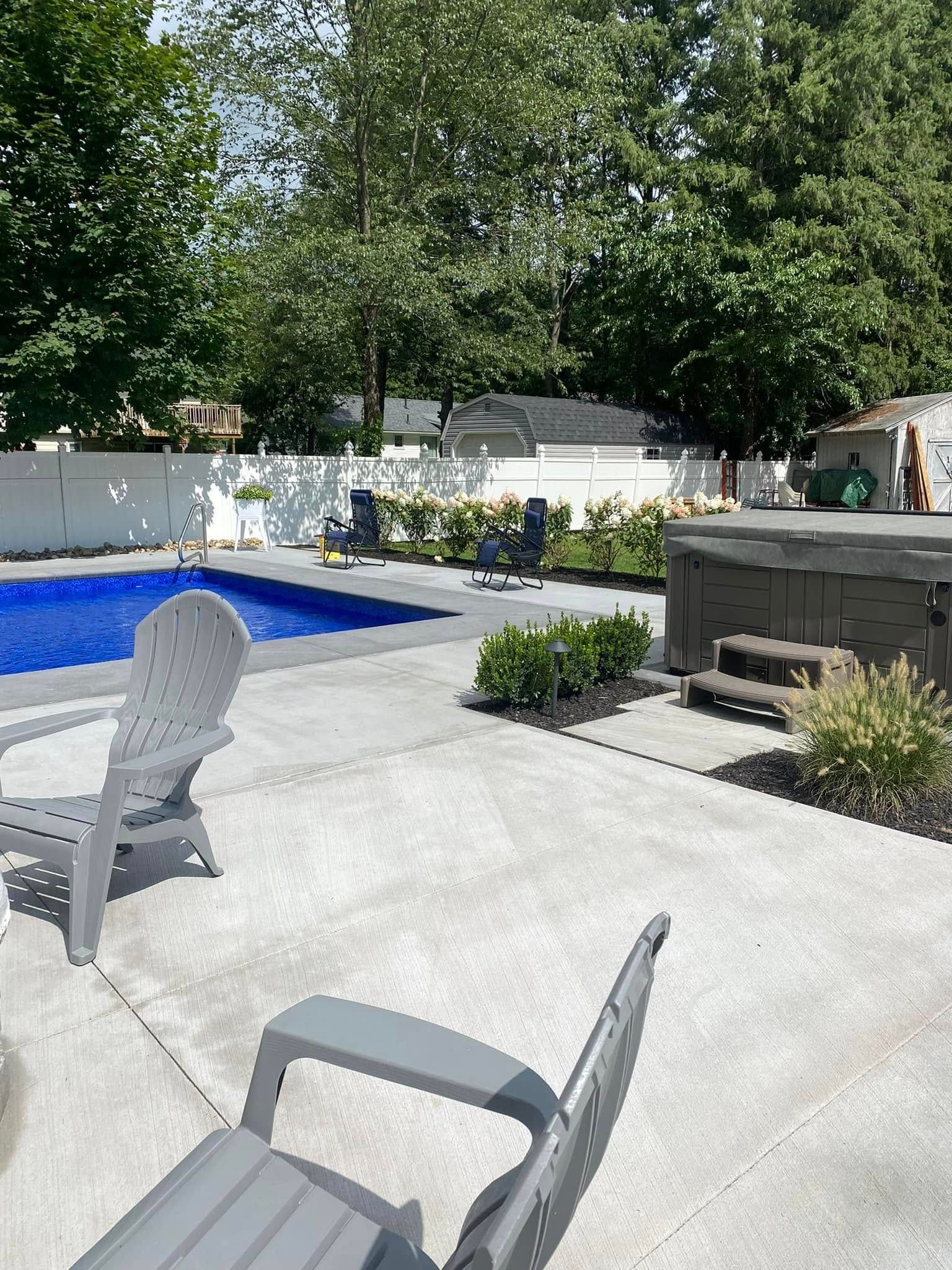 A patio with chairs and a table next to a pool.