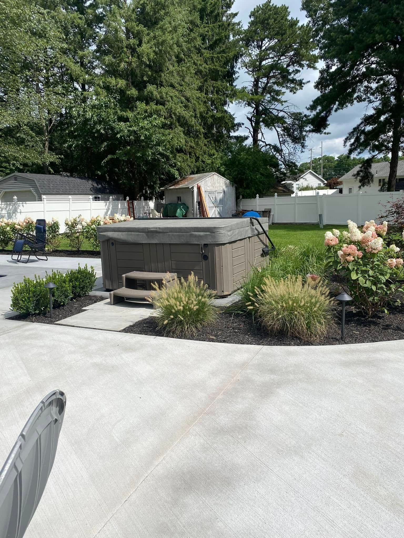 A hot tub is sitting on top of a concrete driveway in a backyard.