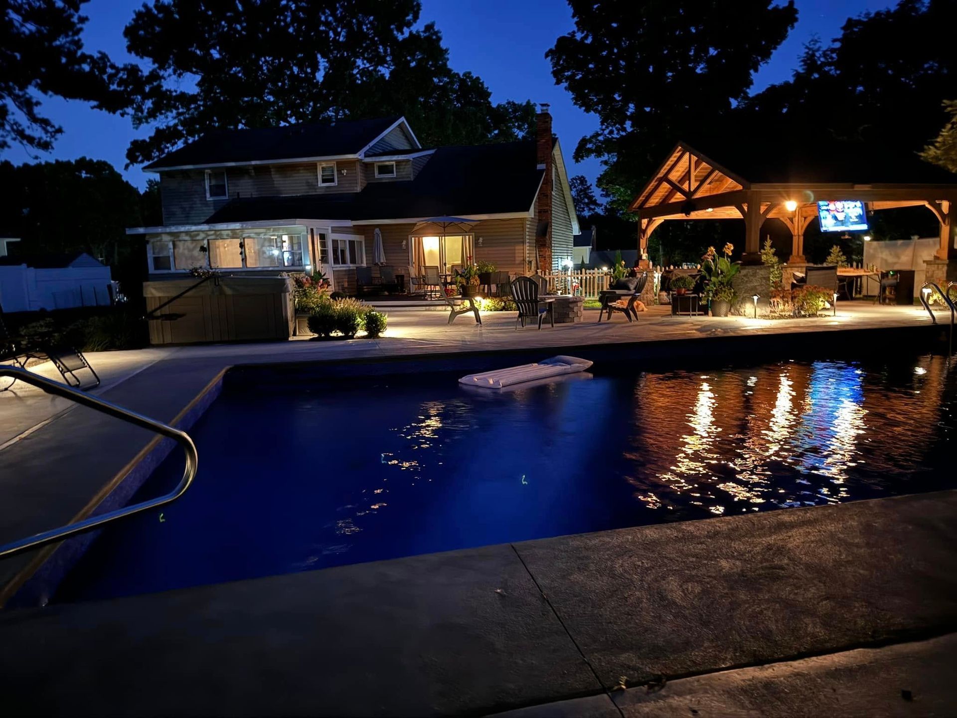 A large swimming pool in front of a house at night