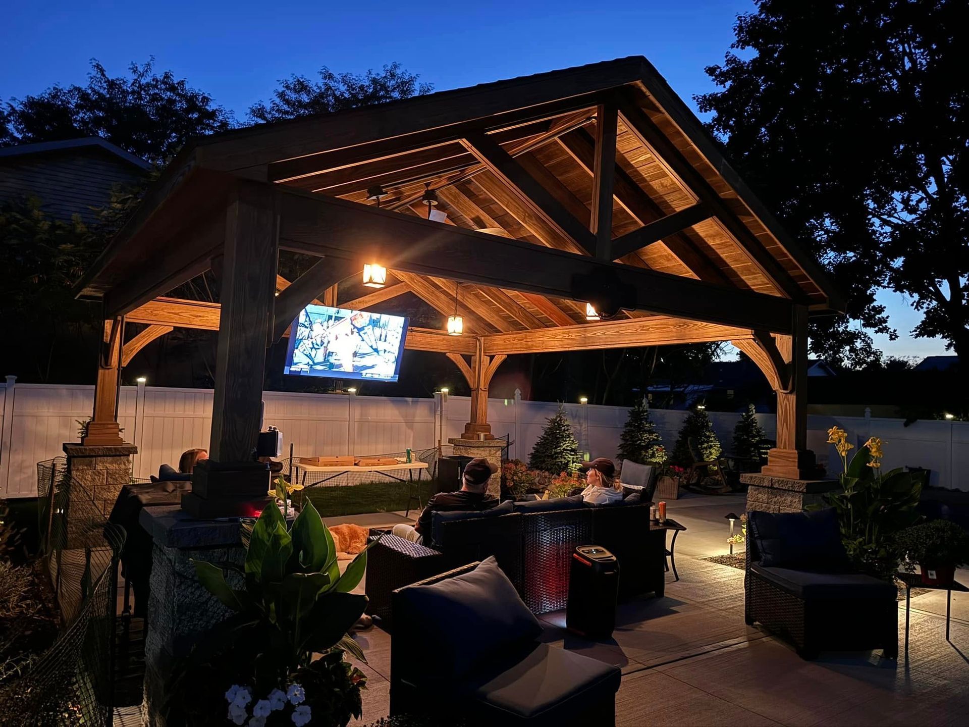 A wooden gazebo with a flat screen tv hanging from the ceiling