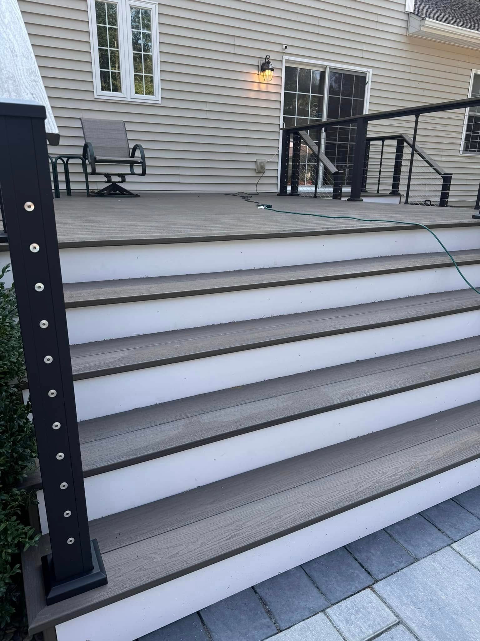 A deck with stairs leading up to it and a black railing.