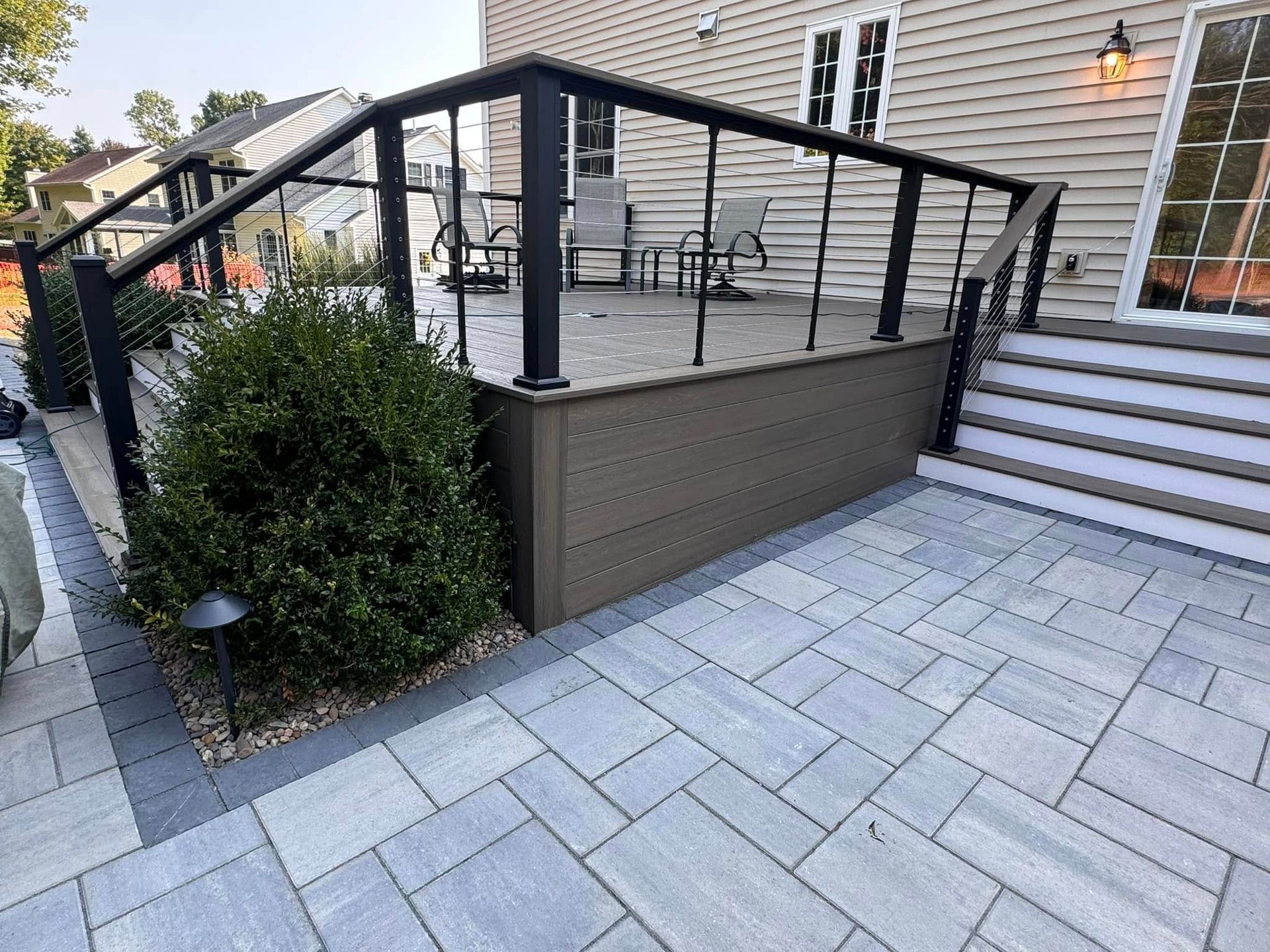 A patio with a deck and stairs in front of a house.