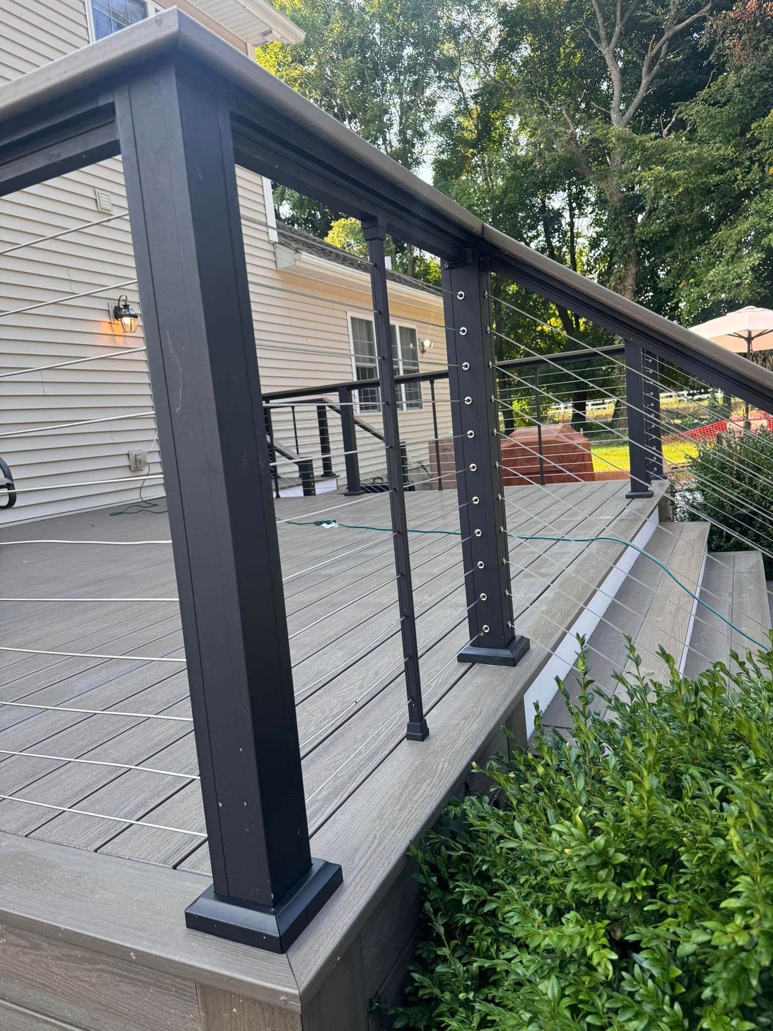 A wooden deck with a metal railing and stairs leading up to it.