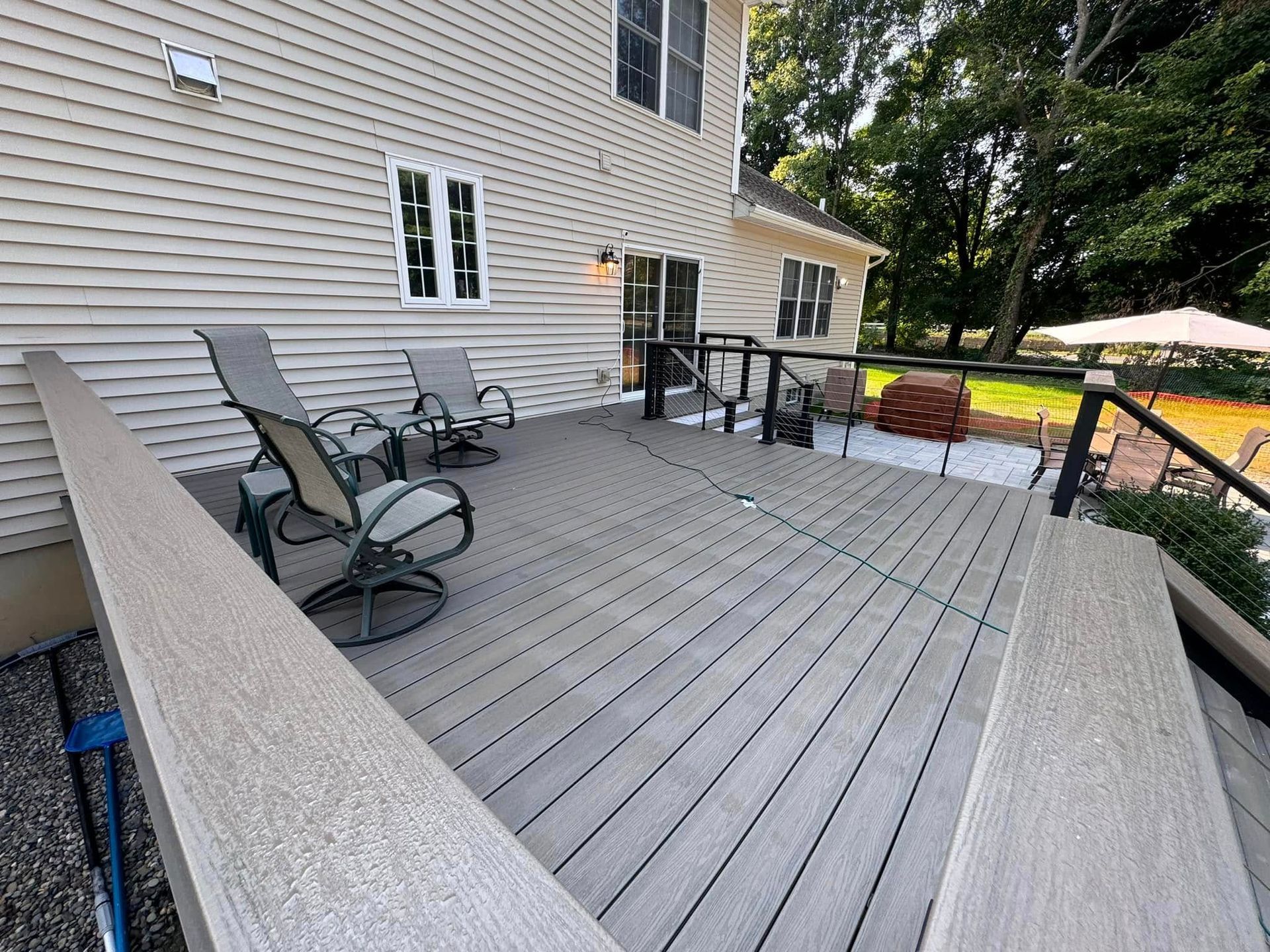A large deck with chairs and umbrellas in front of a house.