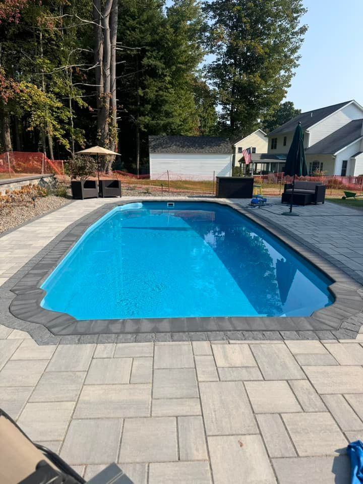 A large swimming pool with a patio in front of it
