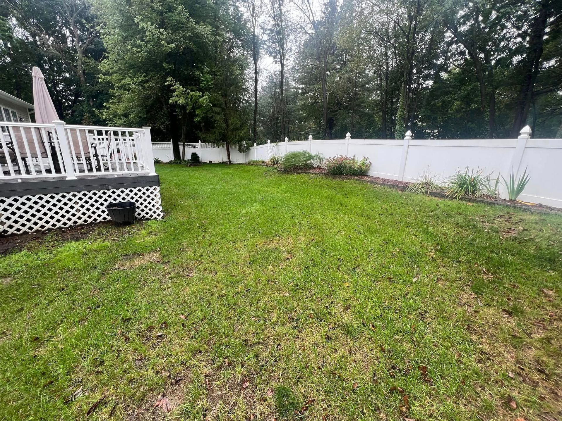 A backyard with a white fence and a deck.