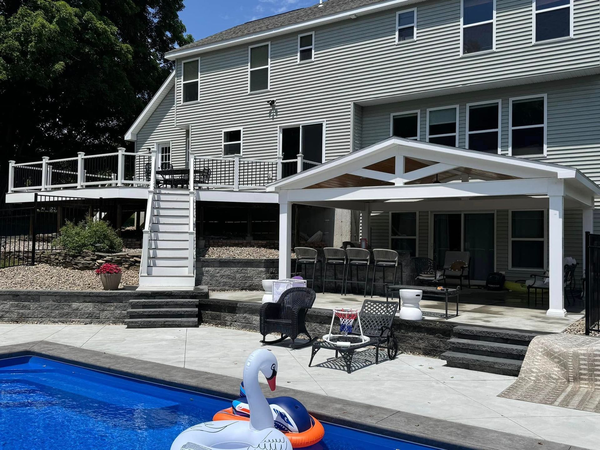 A swan float is floating in a swimming pool in front of a house.