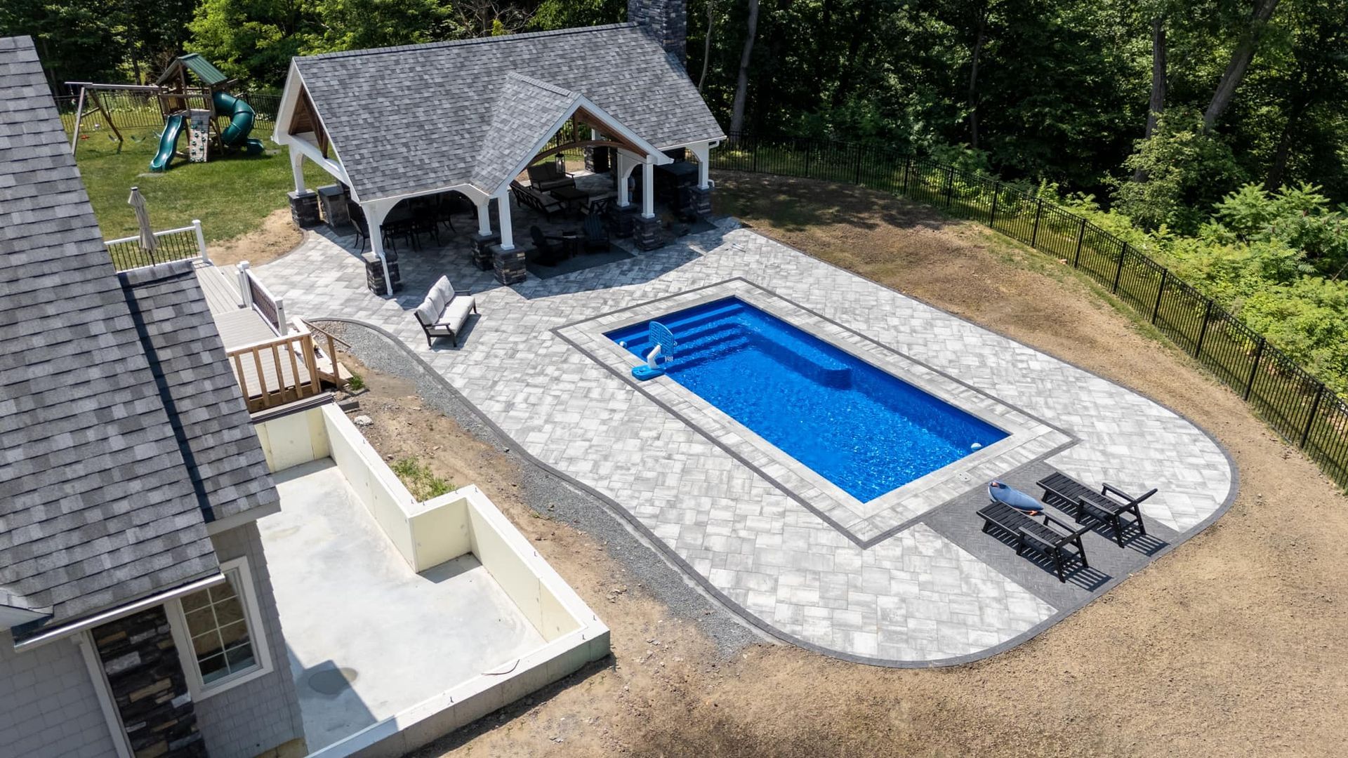 An aerial view of a large swimming pool in the backyard of a house.