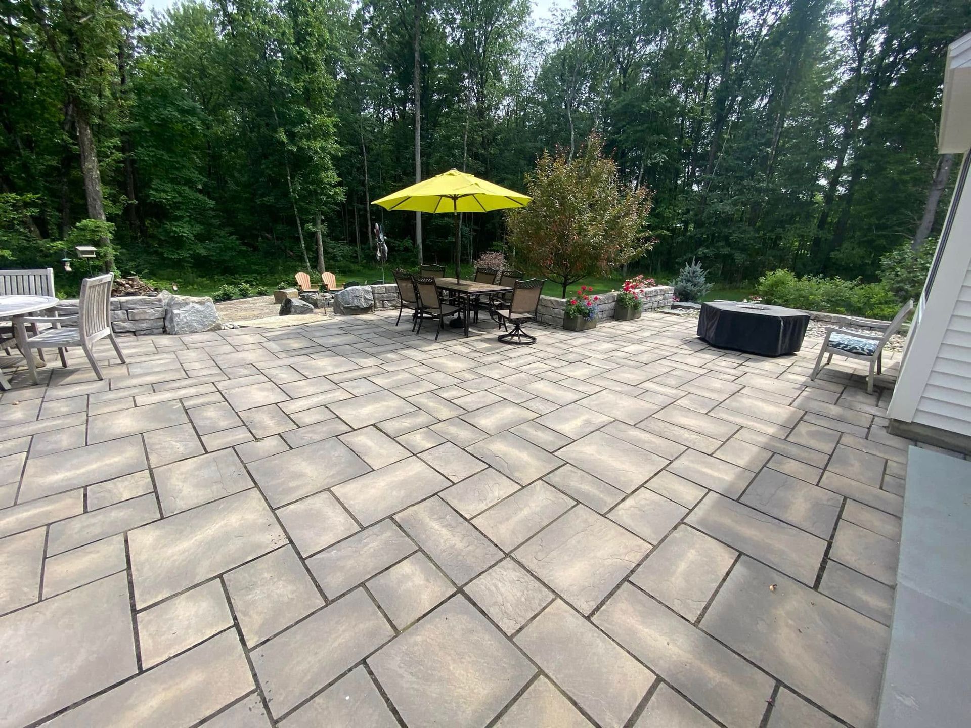 A large patio with a table and chairs and a yellow umbrella.