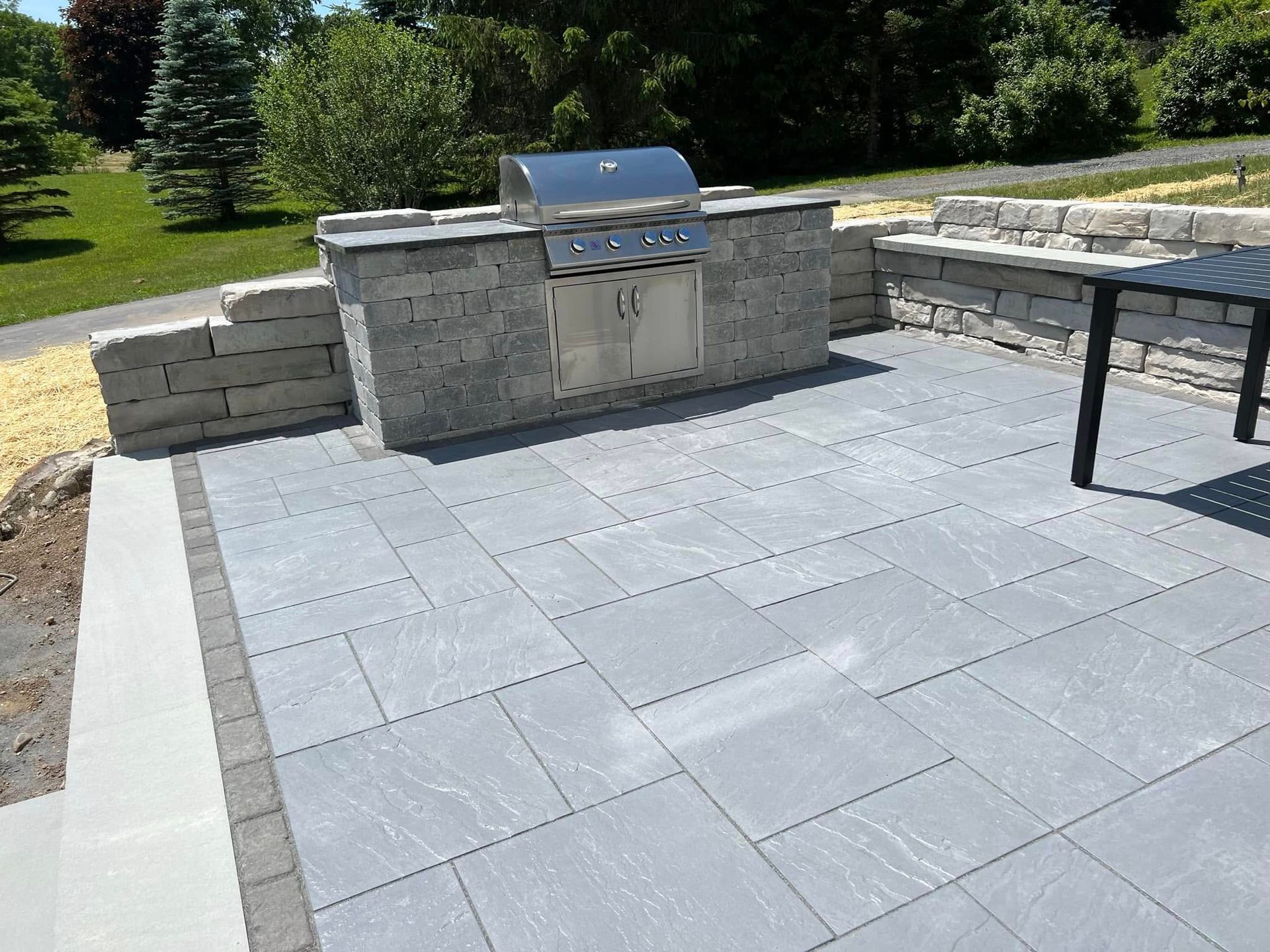 A patio with a grill and a table on it