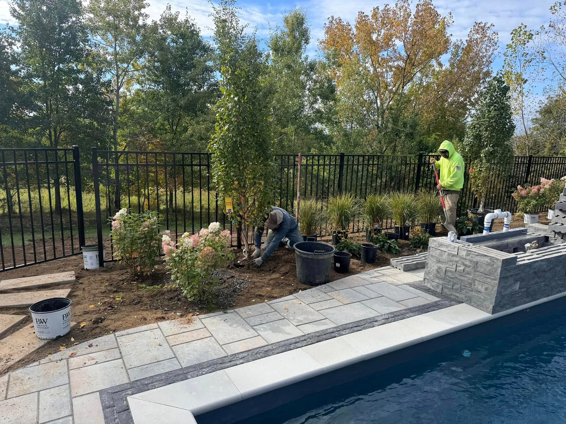 A group of people are working on a fence around a pool.