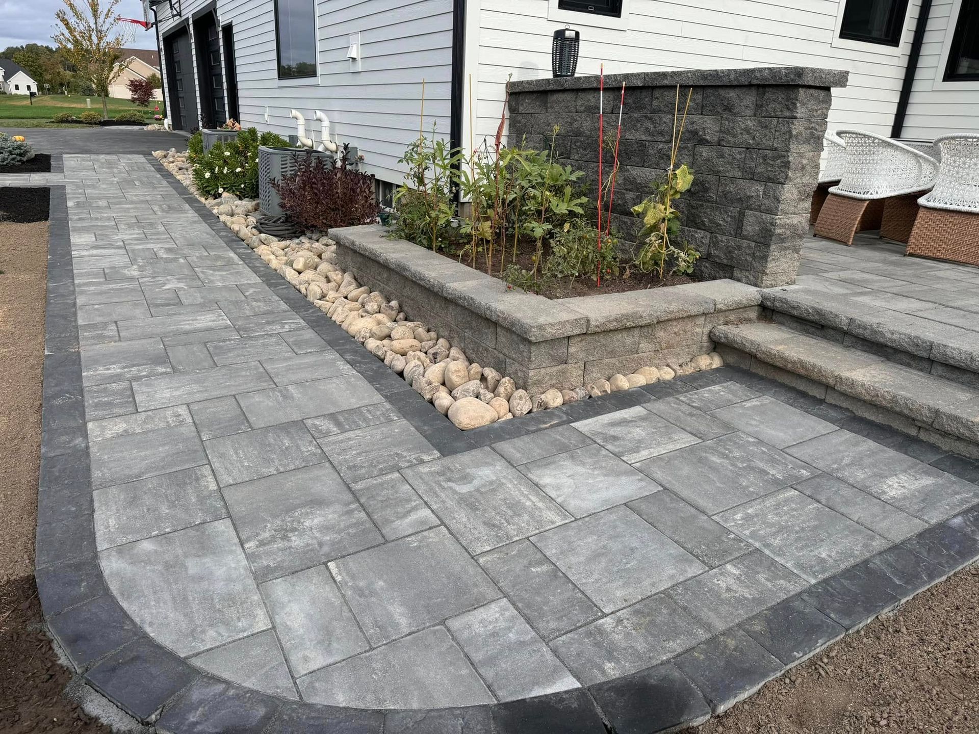 A walkway leading to a house with a planter and steps.
