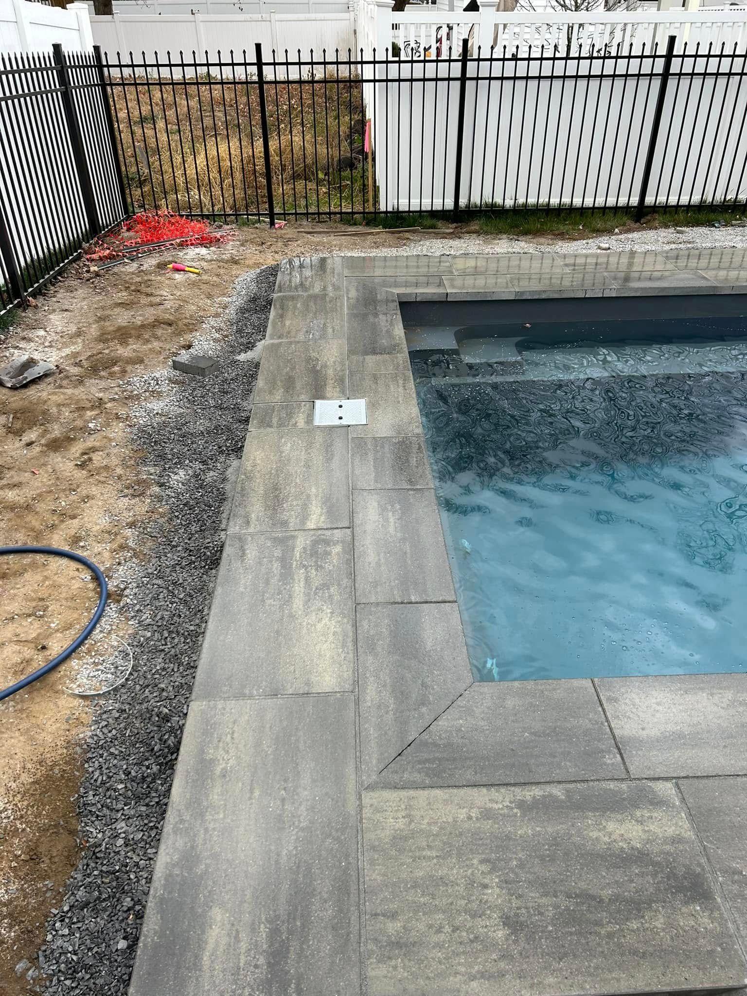A swimming pool is being built in a backyard next to a fence.