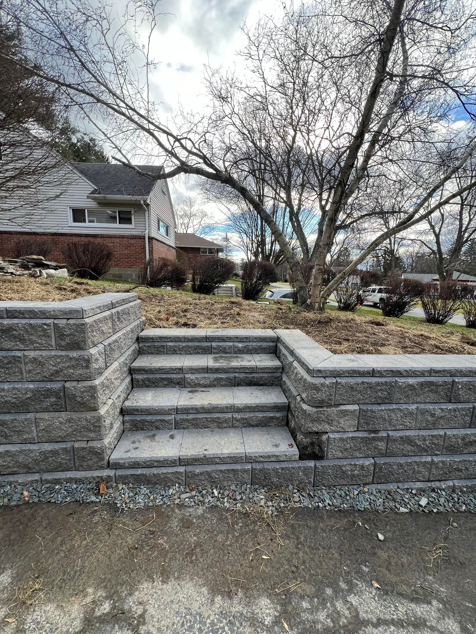 A stone wall with stairs leading up to a house.