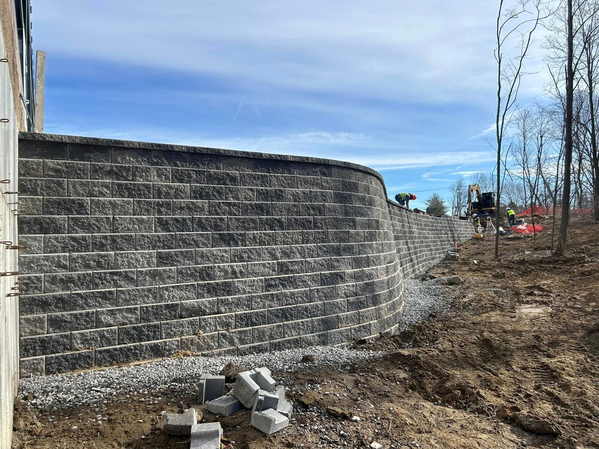 A large brick wall is being built in the middle of a dirt field.