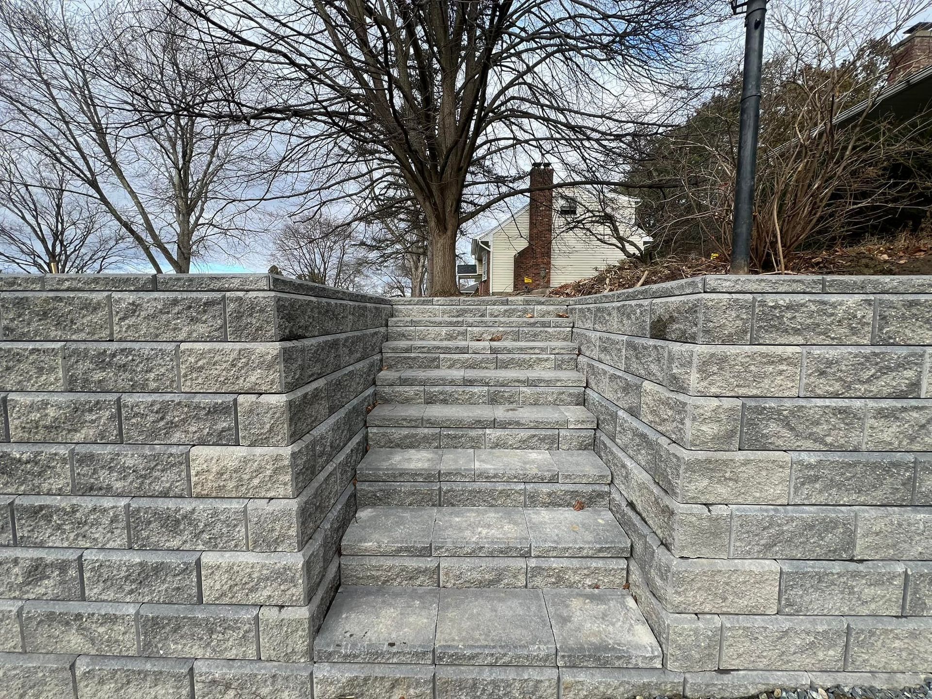 A set of stairs leading up to a stone wall with a tree in the background.