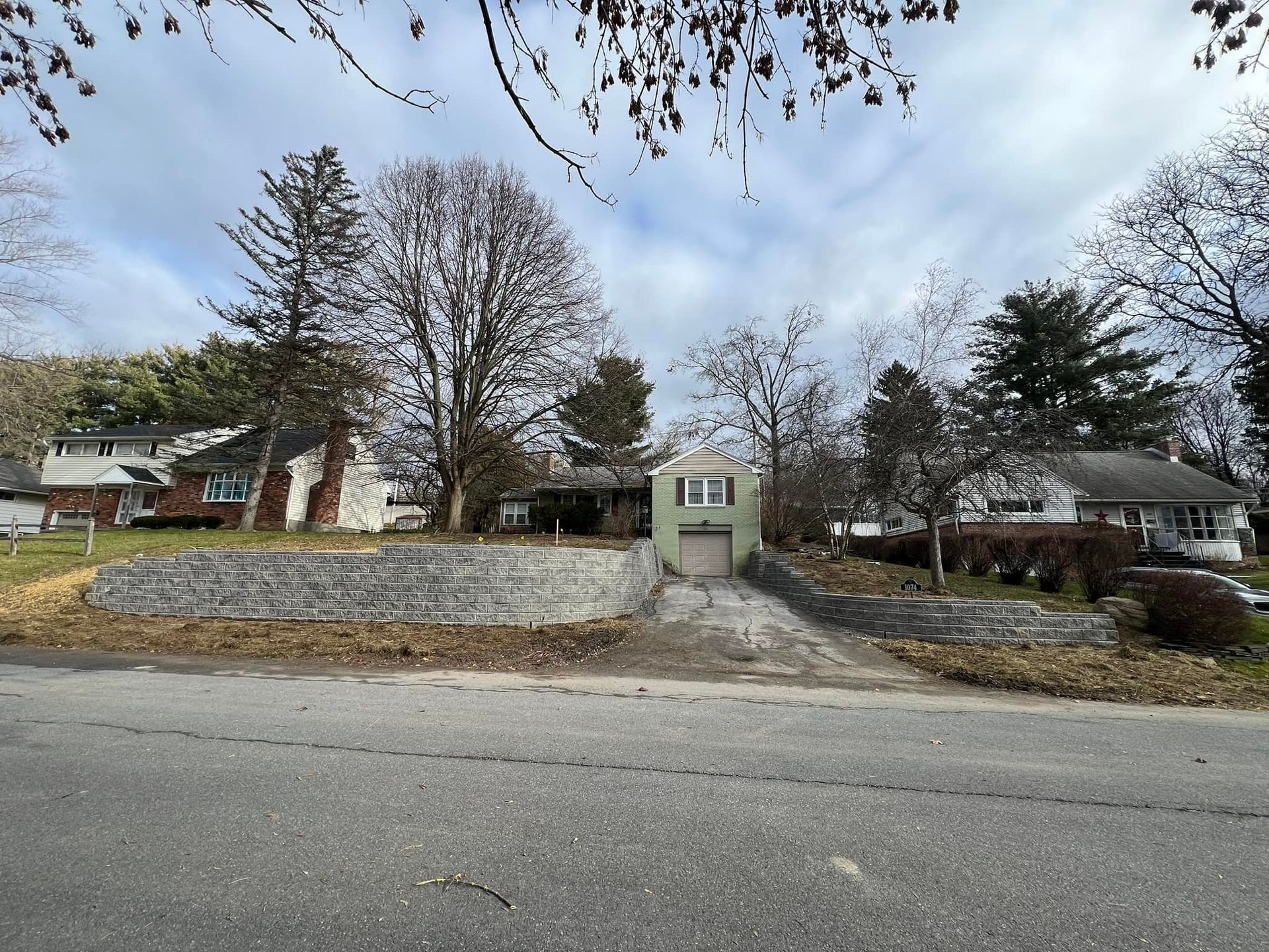 A house is sitting on the side of the road next to a garage.