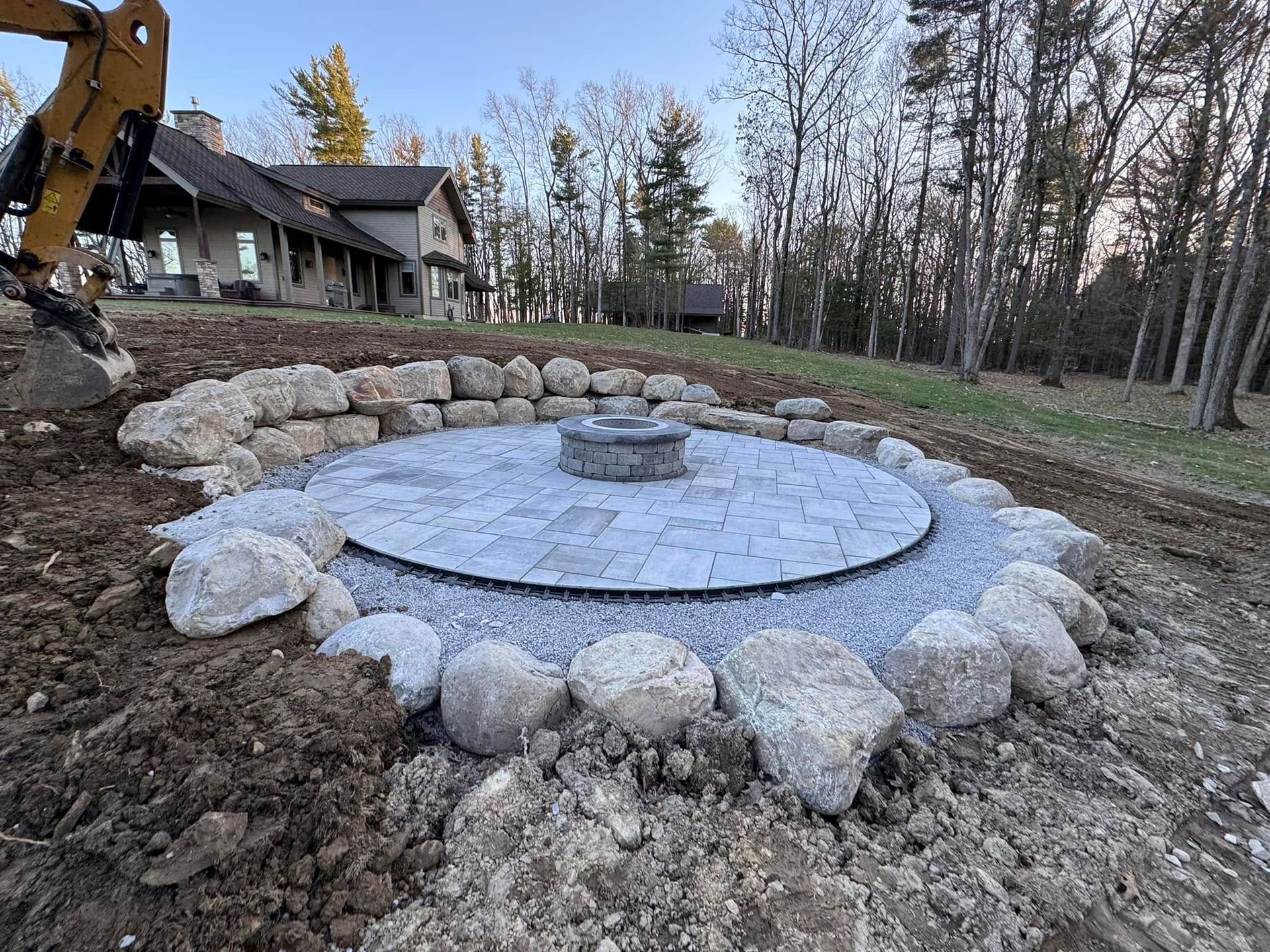 A fire pit is being built in the dirt in front of a house.