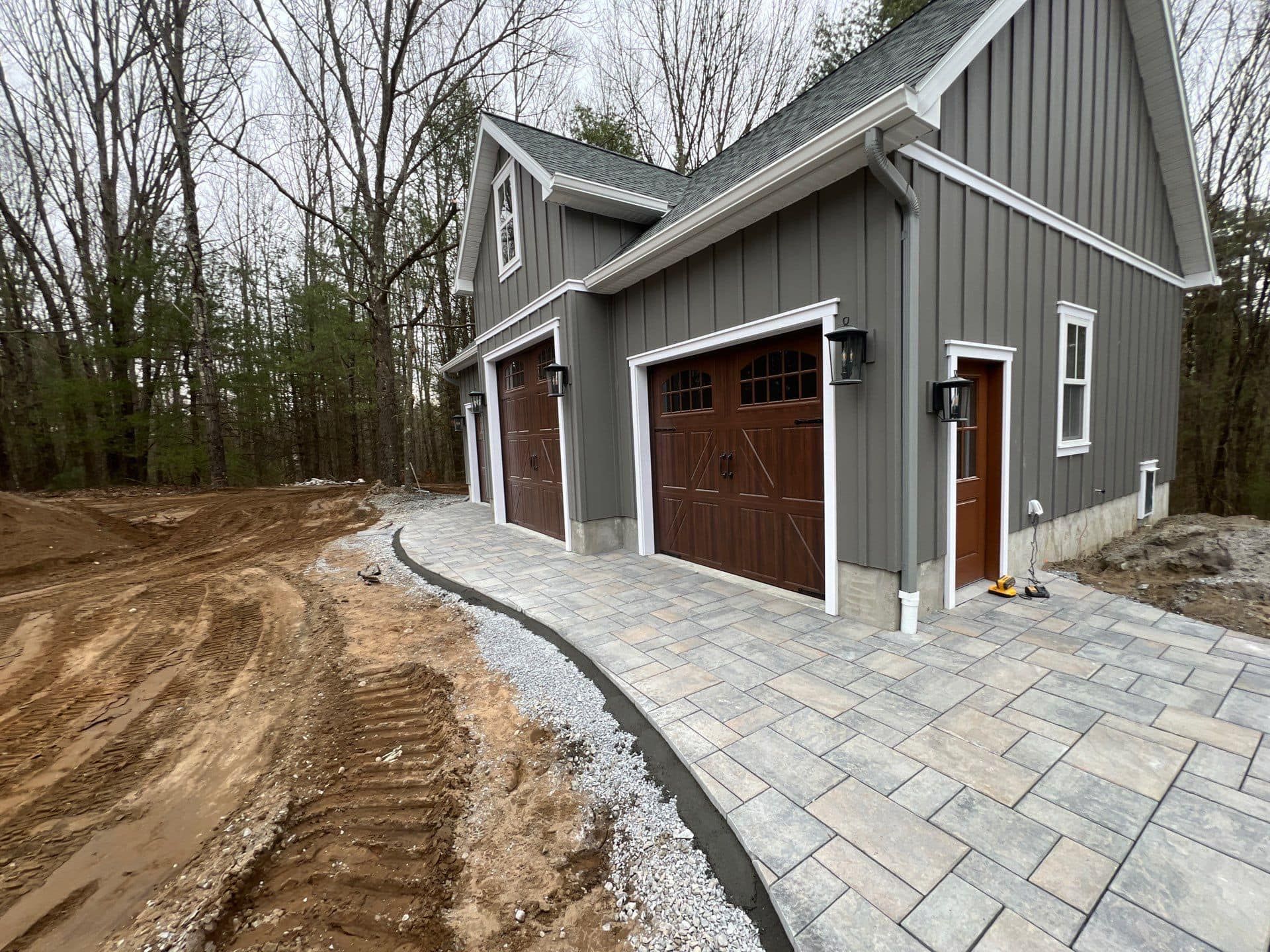 A gray house with three garage doors and a driveway in front of it.