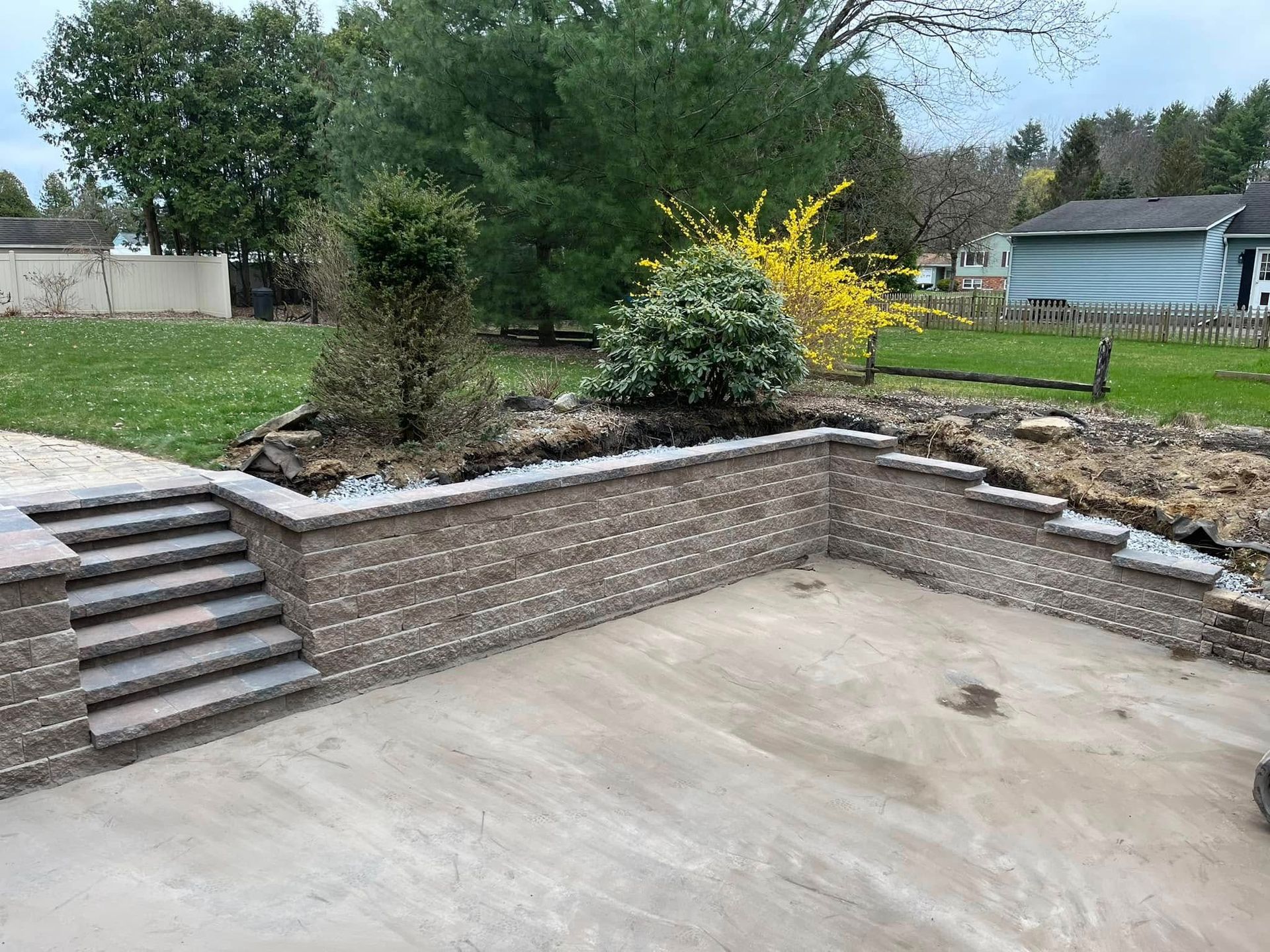 A brick wall with stairs leading up to it in a backyard.