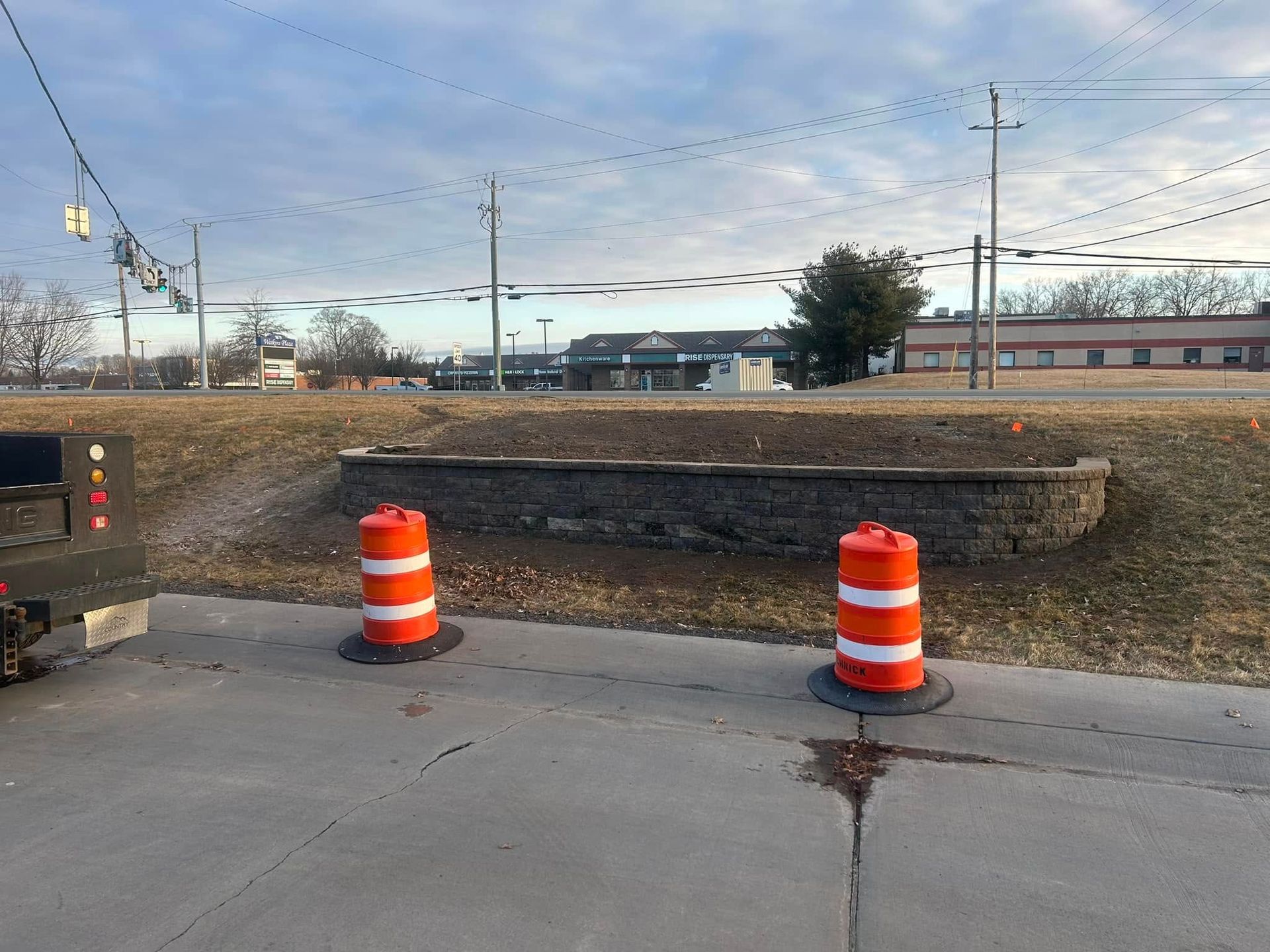 Two orange and white traffic cones are on the side of the road.