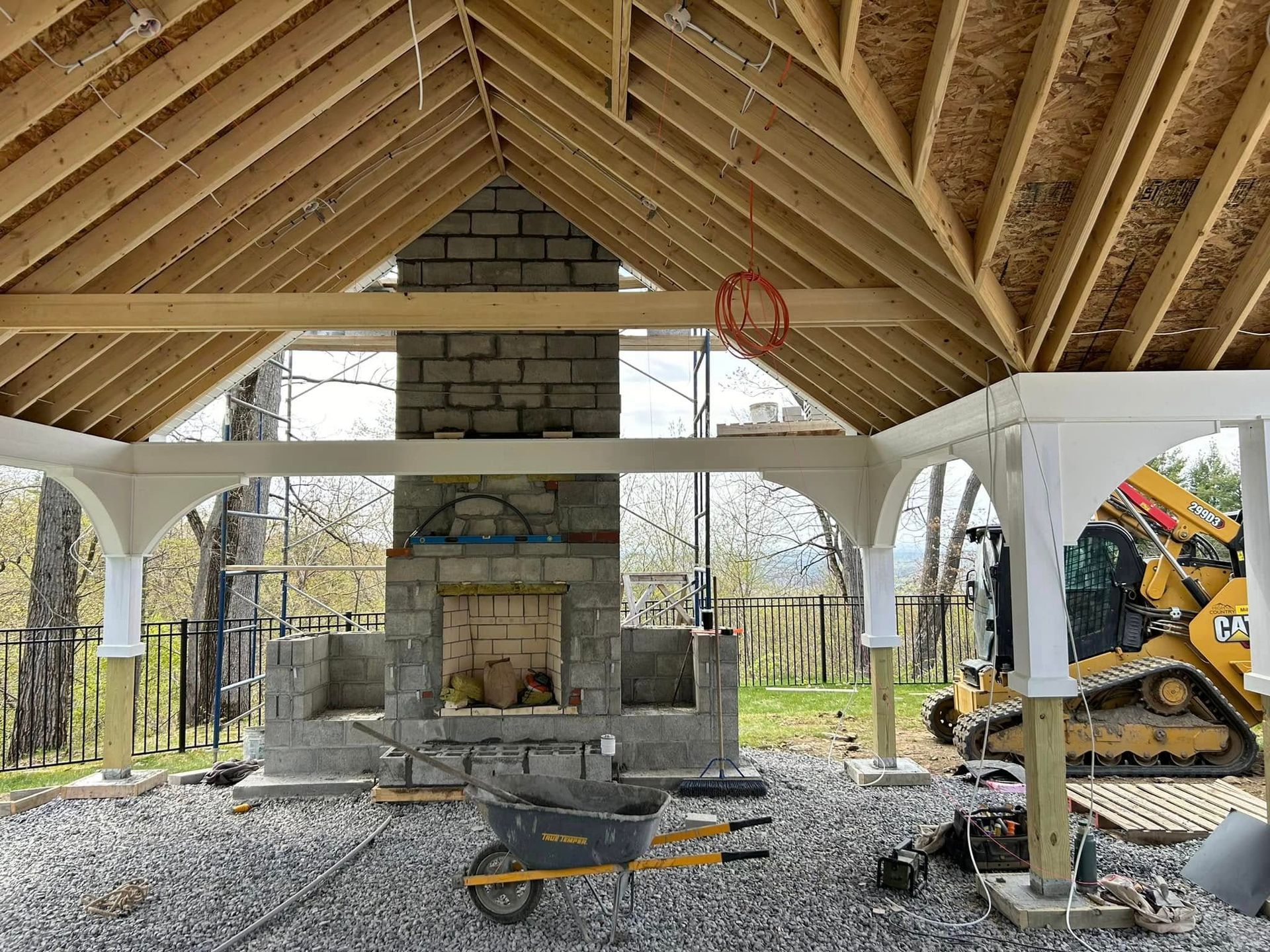 A building under construction with a brick fireplace and a wheelbarrow.