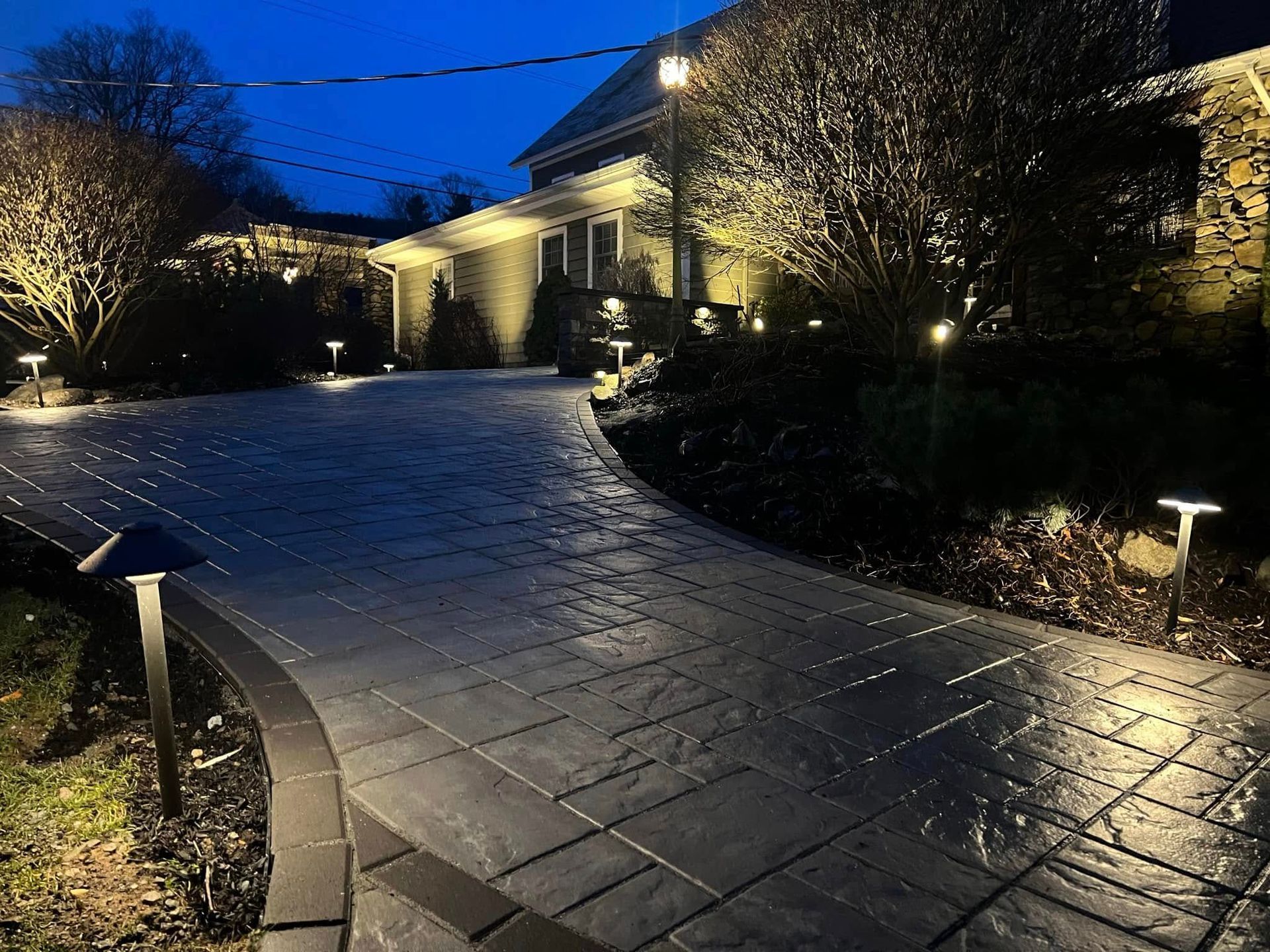 A driveway is lit up at night in front of a house.