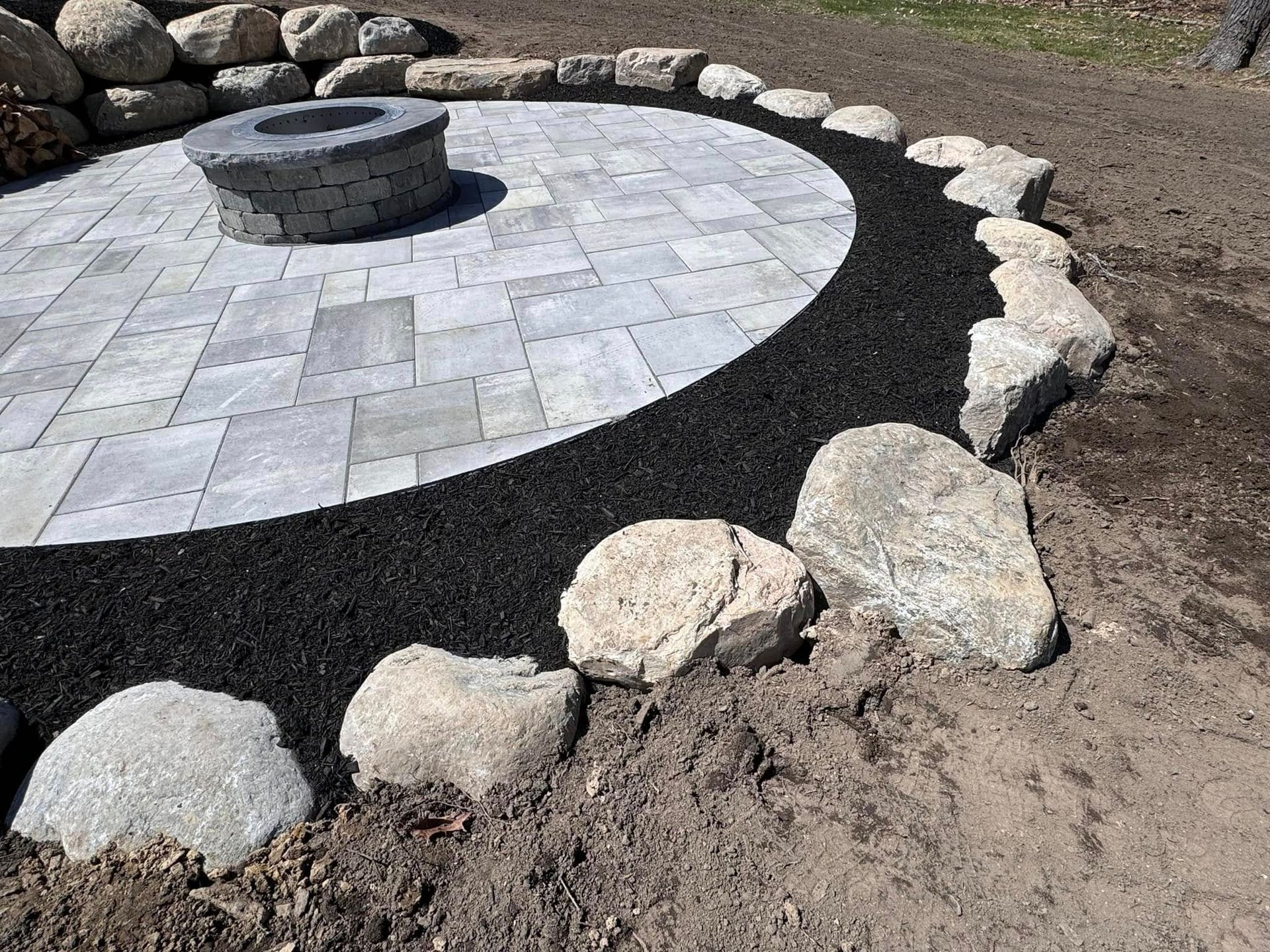 There is a fire pit in the middle of the patio surrounded by rocks.