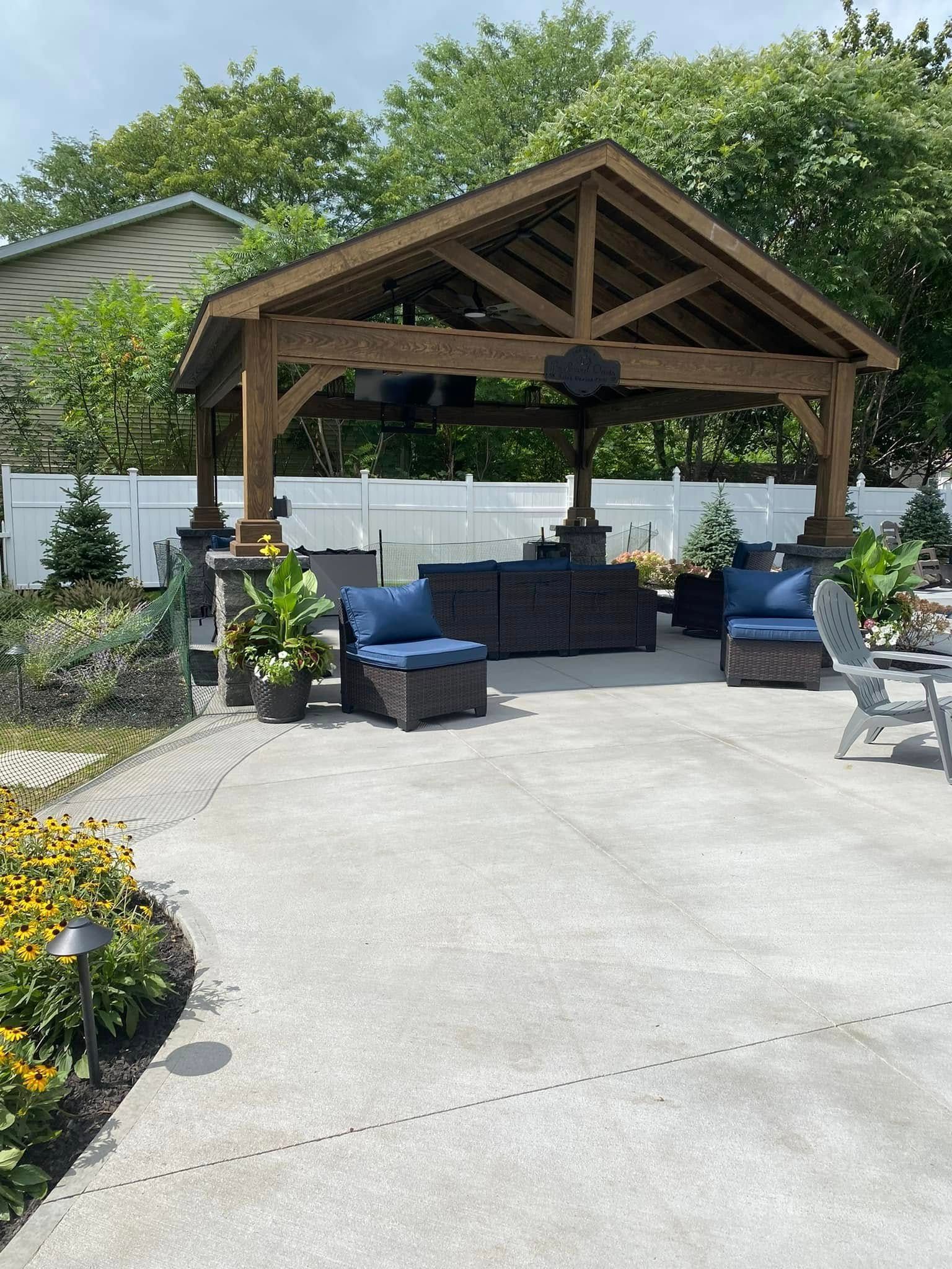 Patio with a wooden gazebo, seating, and surrounding landscaping.