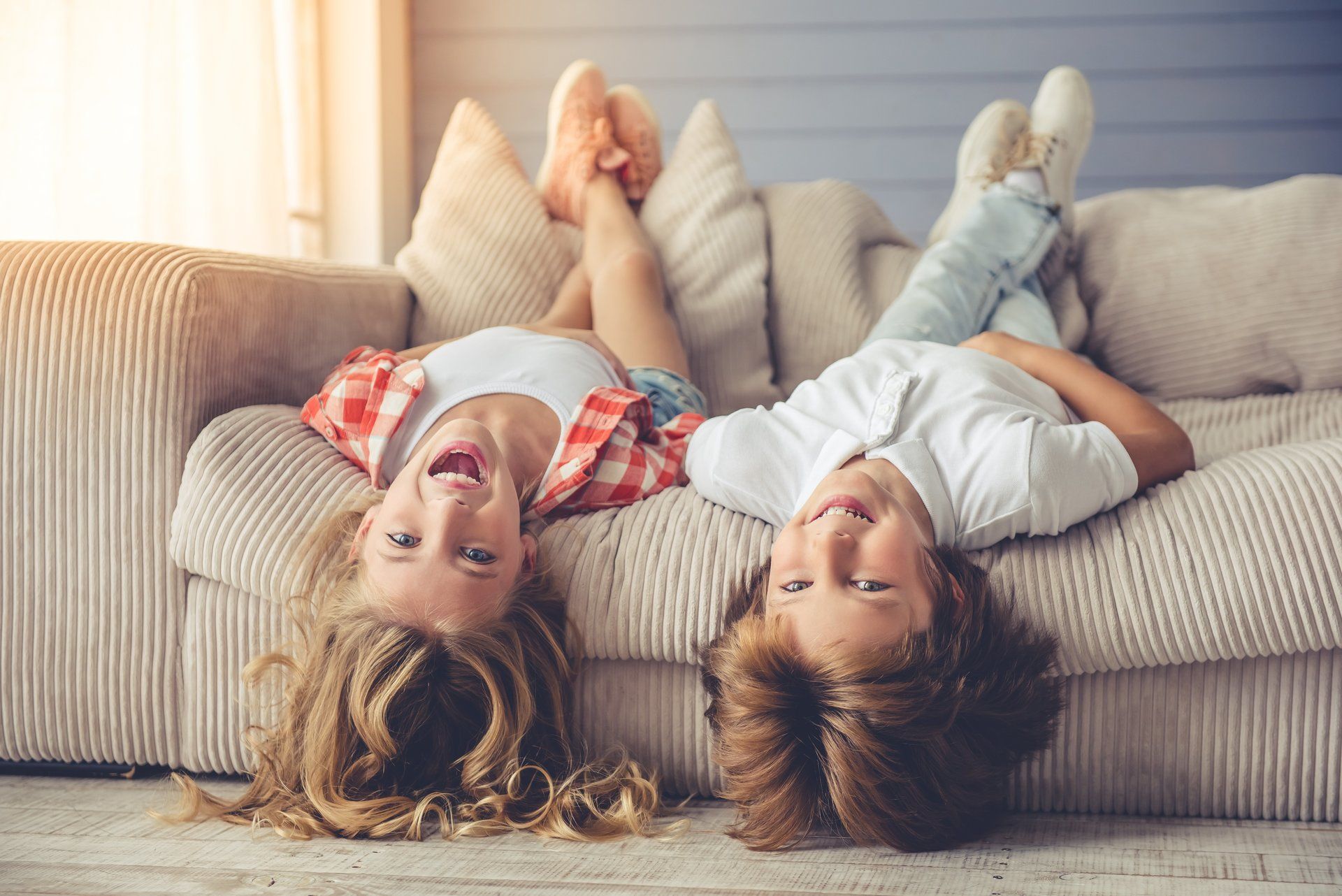 A girl and boy lying upside down on the couch