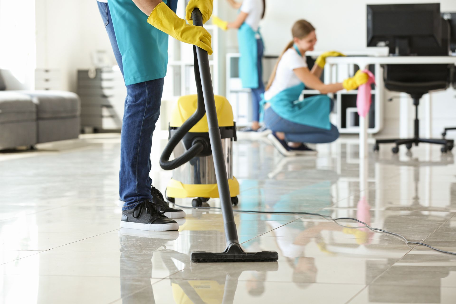 A man is using a vacuum cleaner to clean the floor in an office.