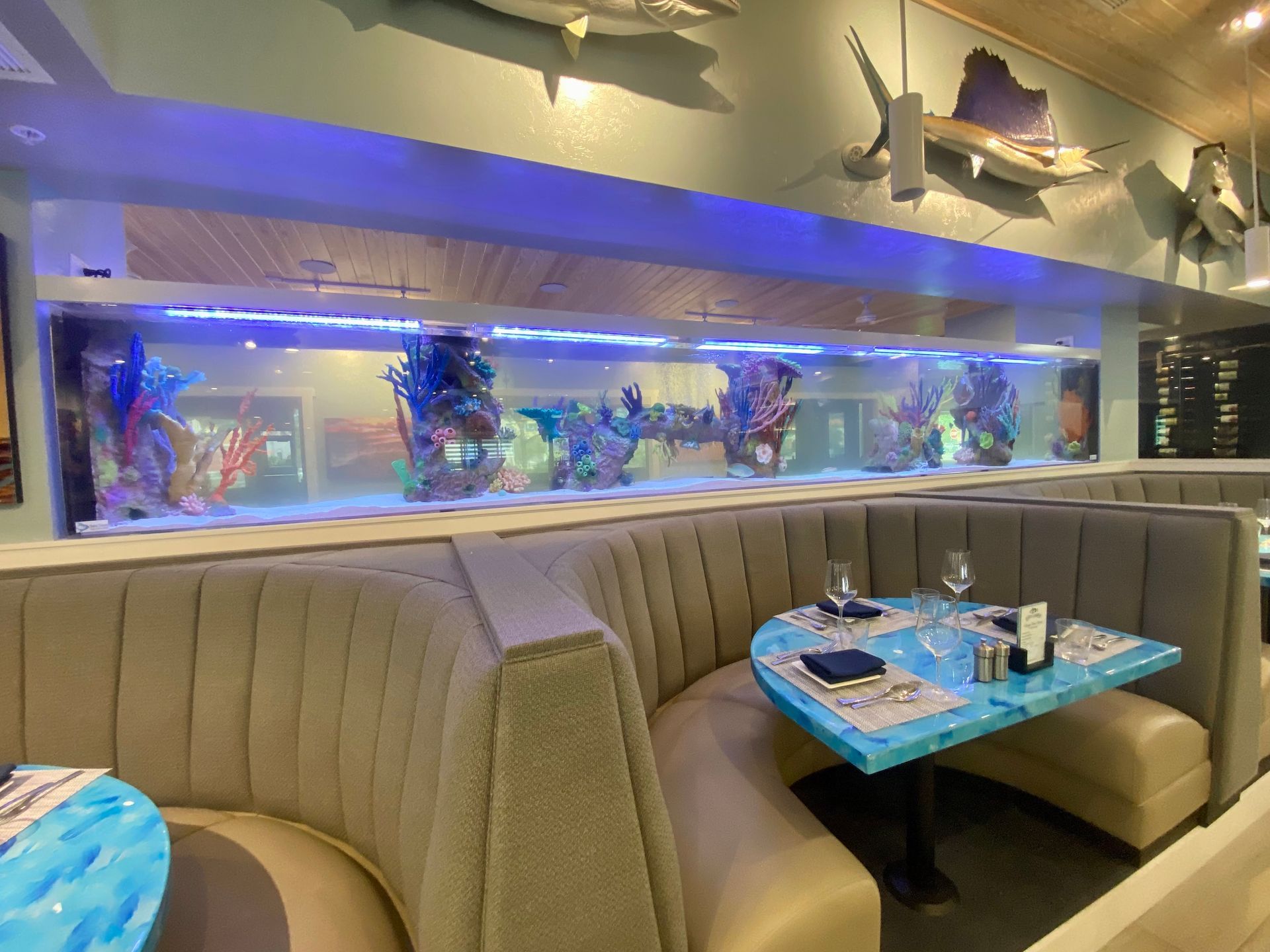 Restaurant interior with large aquarium, booth seating, and fish decor. Tables set for dining.