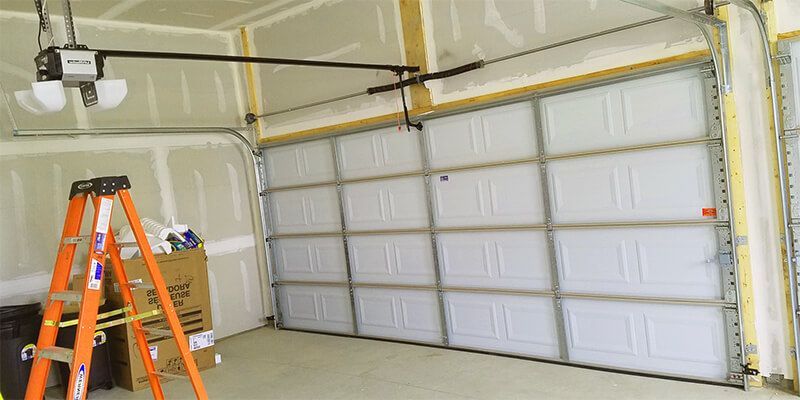 Garage interior with a partially open white door, orange ladder, and garage door opener.