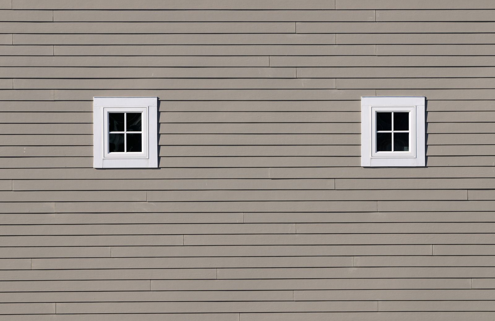 There are two windows on the side of a house.