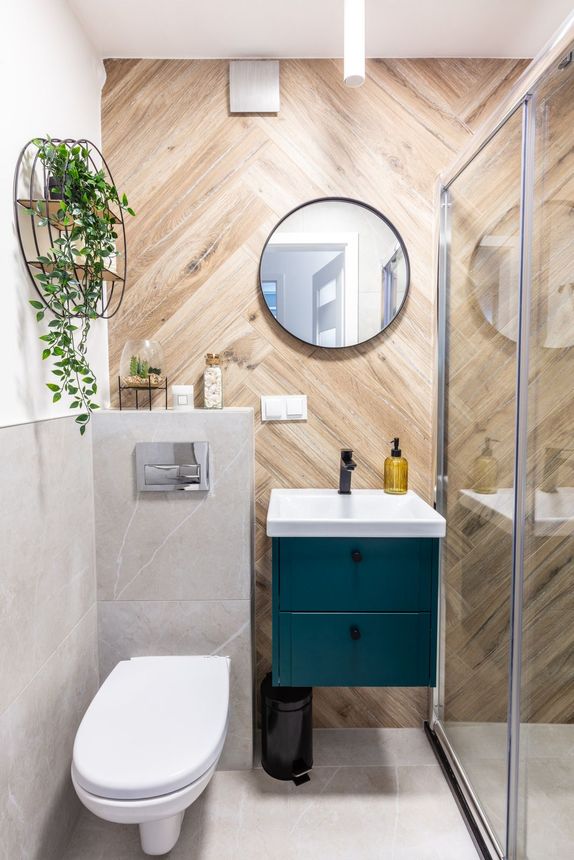 A bathroom with a toilet , sink , mirror and shower.