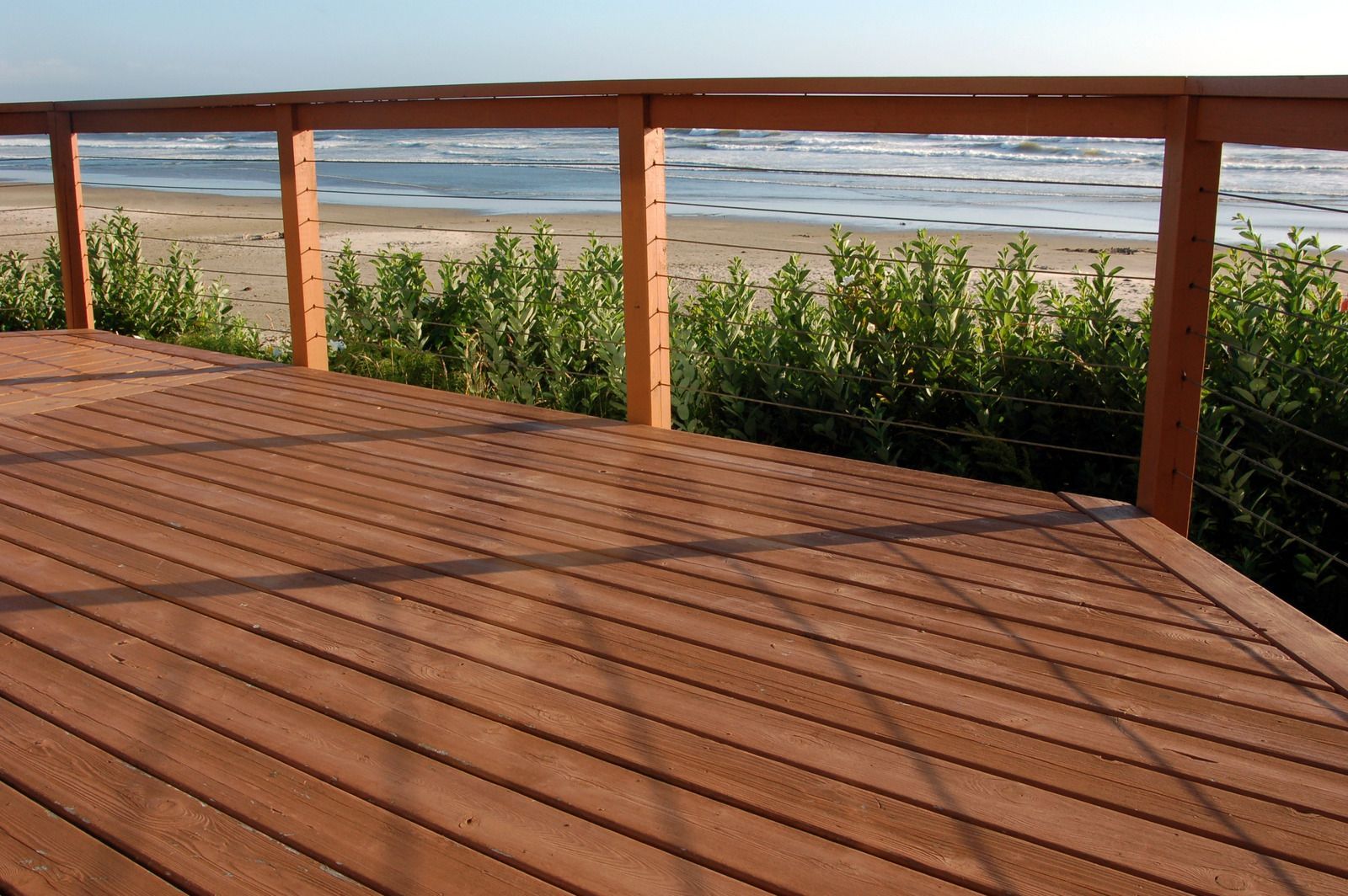 A wooden deck with a railing overlooking the ocean