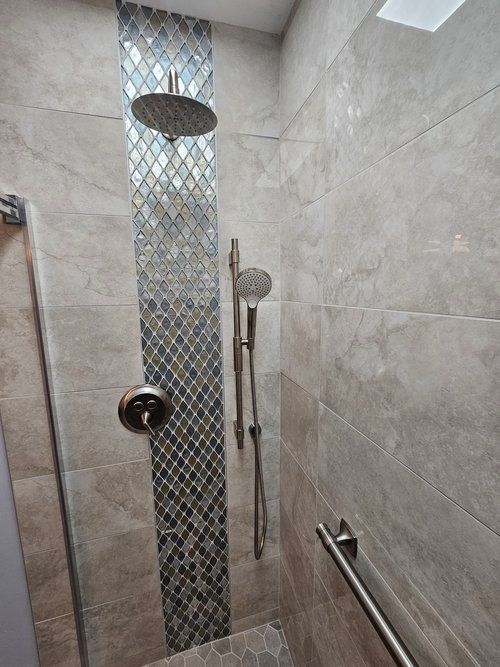 A shower with a glass door and two shower heads.