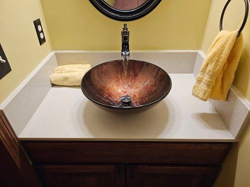 A bathroom with a round sink and a mirror