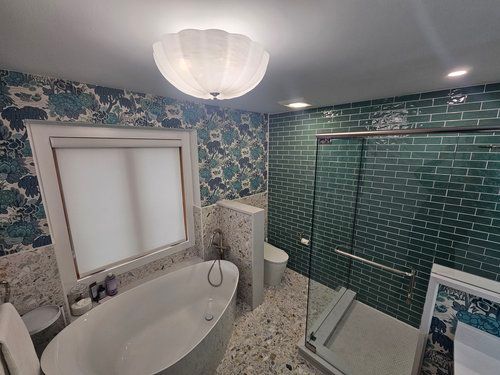 A bathroom with a tub , toilet , shower and window.