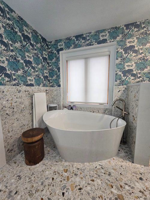A bathroom with a bathtub , sink , and window.