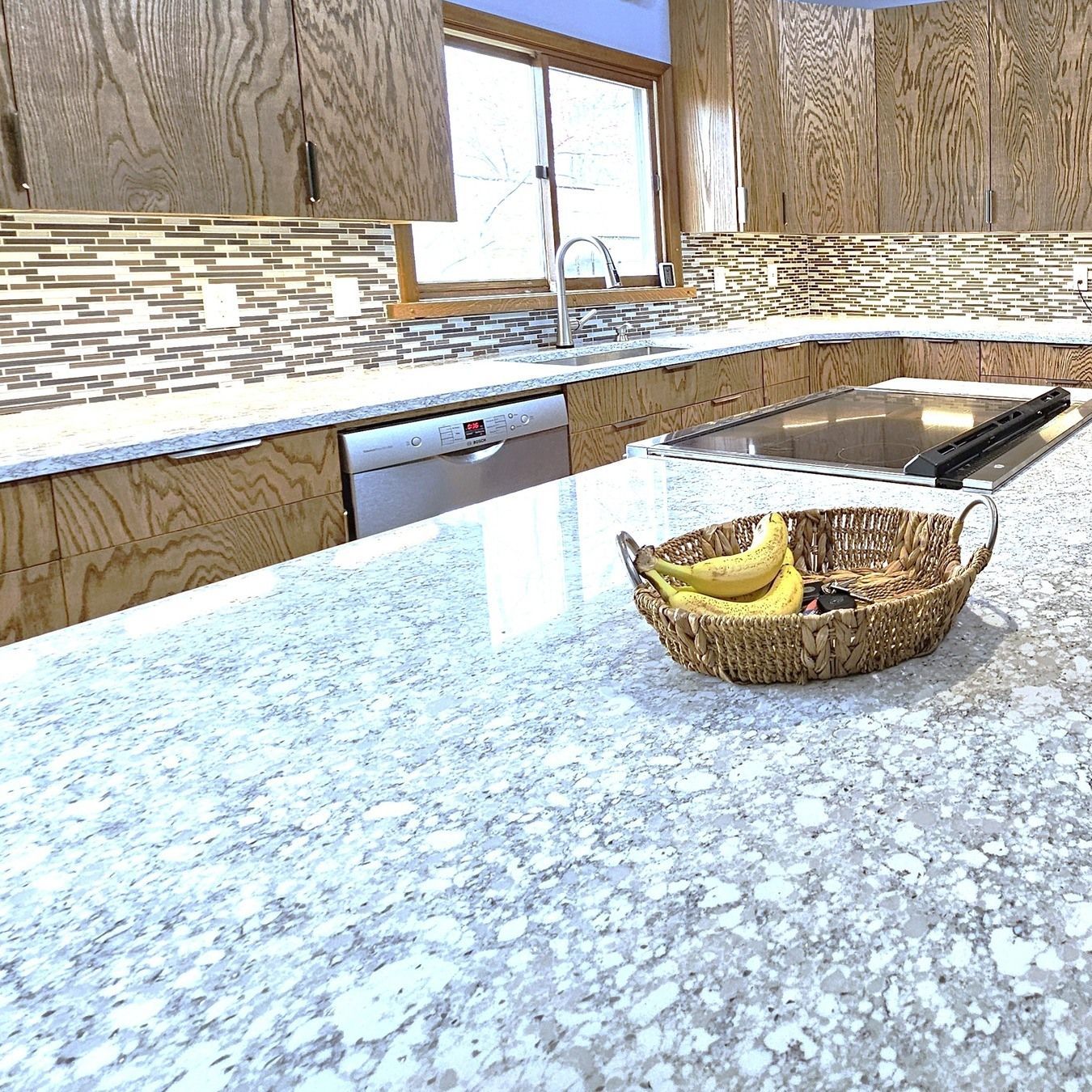 A kitchen counter with a basket of bananas on it.