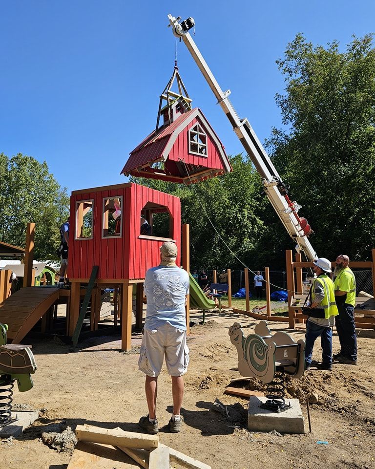 A crane is lifting a red house into a playground