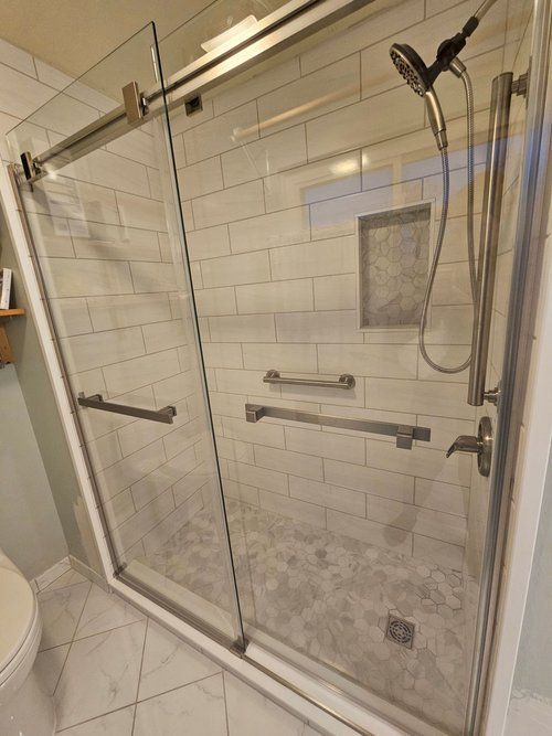A bathroom with a sliding glass shower door and a toilet.