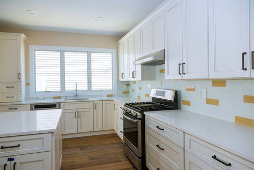 A kitchen with white cabinets , stainless steel appliances , and a large window.