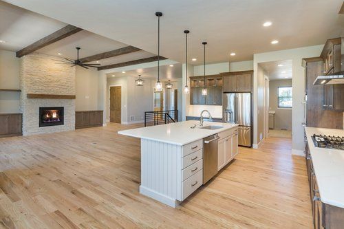 A kitchen with a large island , stainless steel appliances , hardwood floors and a fireplace.