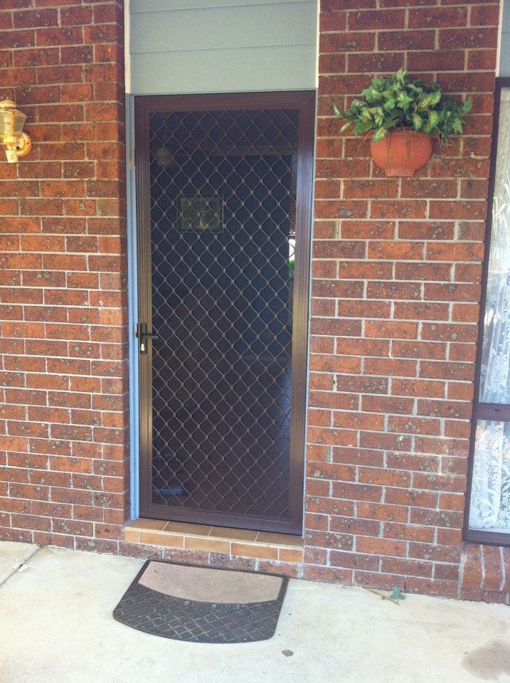 A Brick Building With a Door and a Plant on the Wall — Swift Glass & Aluminium In Woolgoolga, NSW